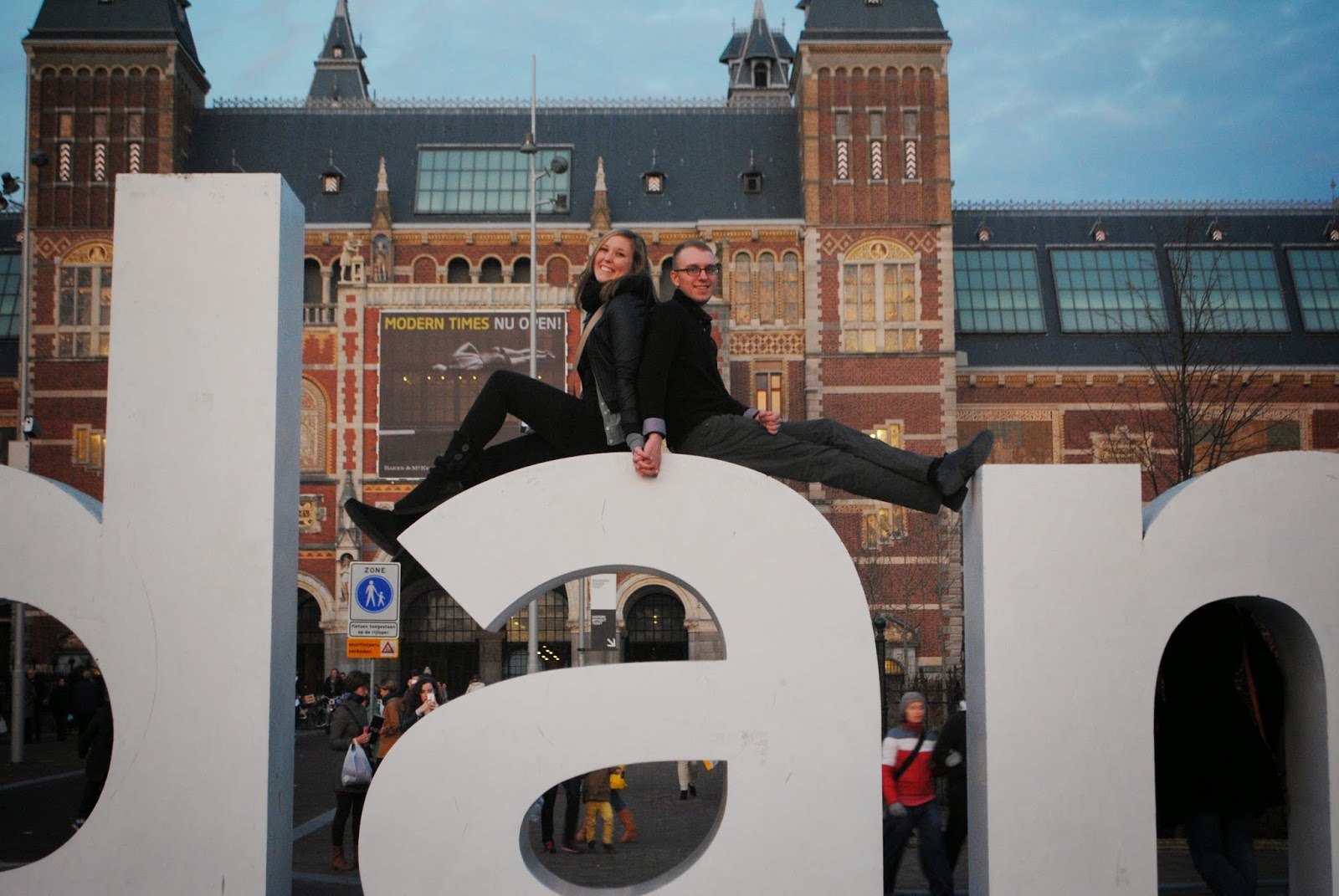 Erinn and Ben sitting on the "I amsterdam" sign in Amsterdam.