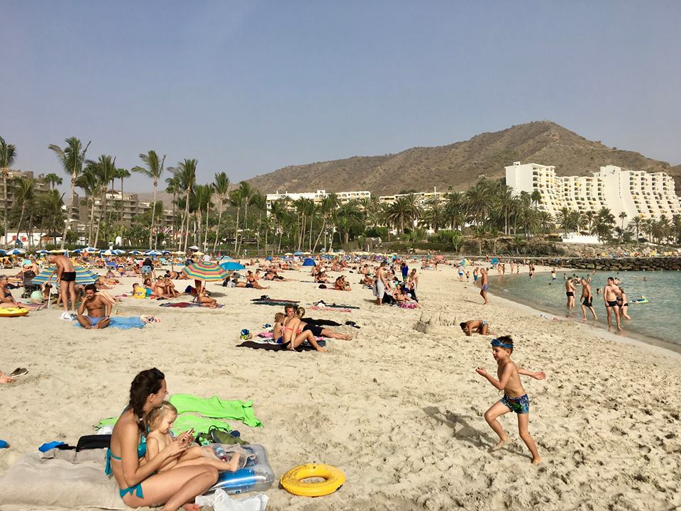 People relaxing in the sand at Playa de Anfi beach.