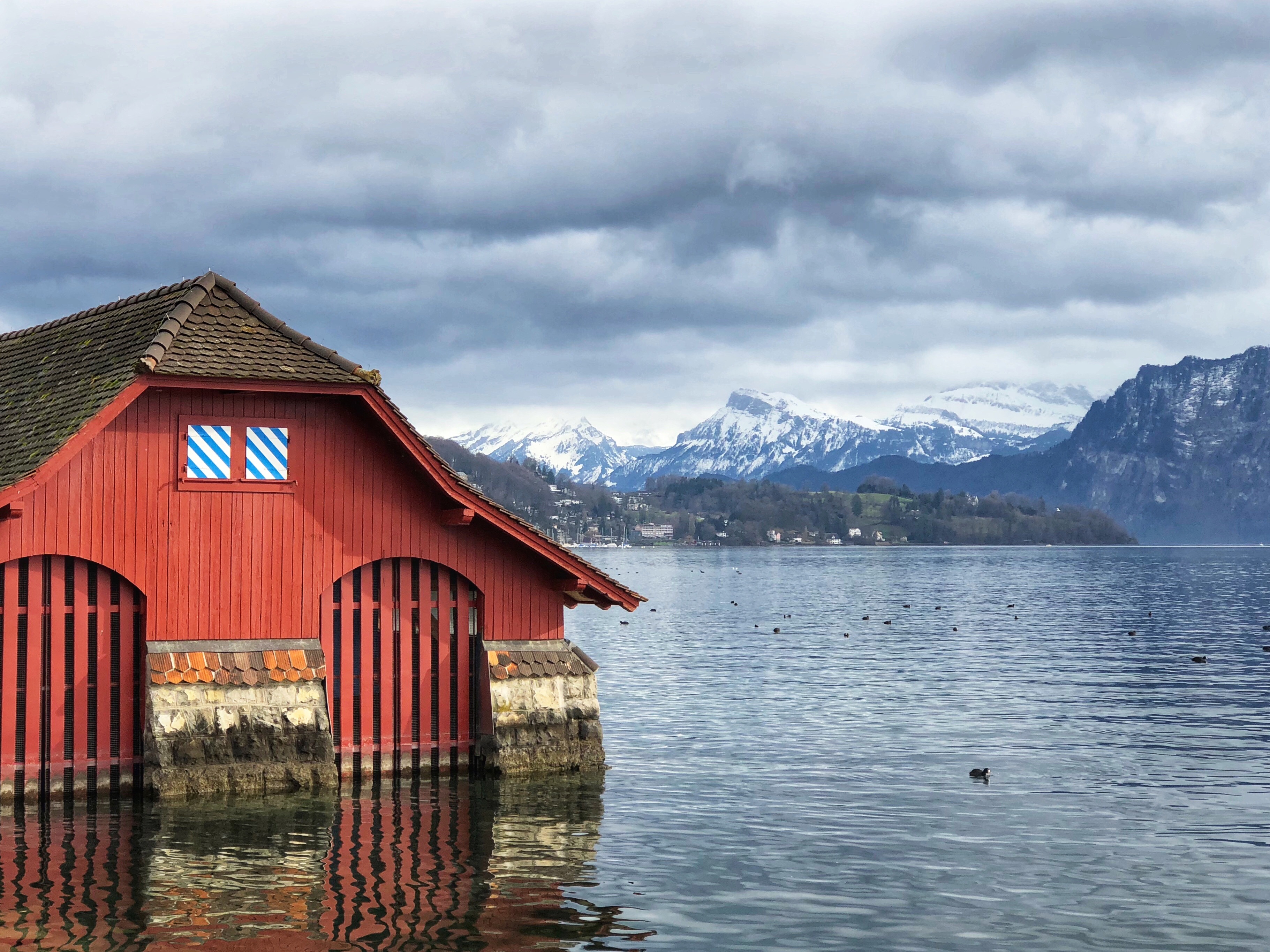 A red building on Lake Lucerne with the snowcapped Alps in the background.