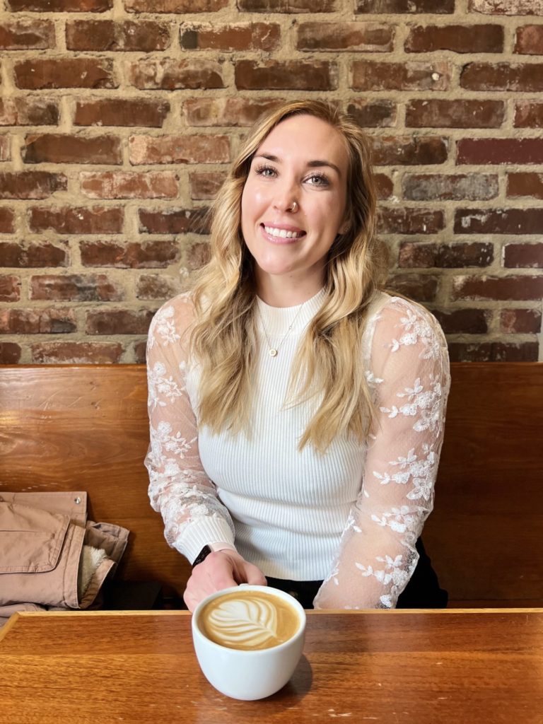Erinn smiles at Frothy Monkey with a latte.