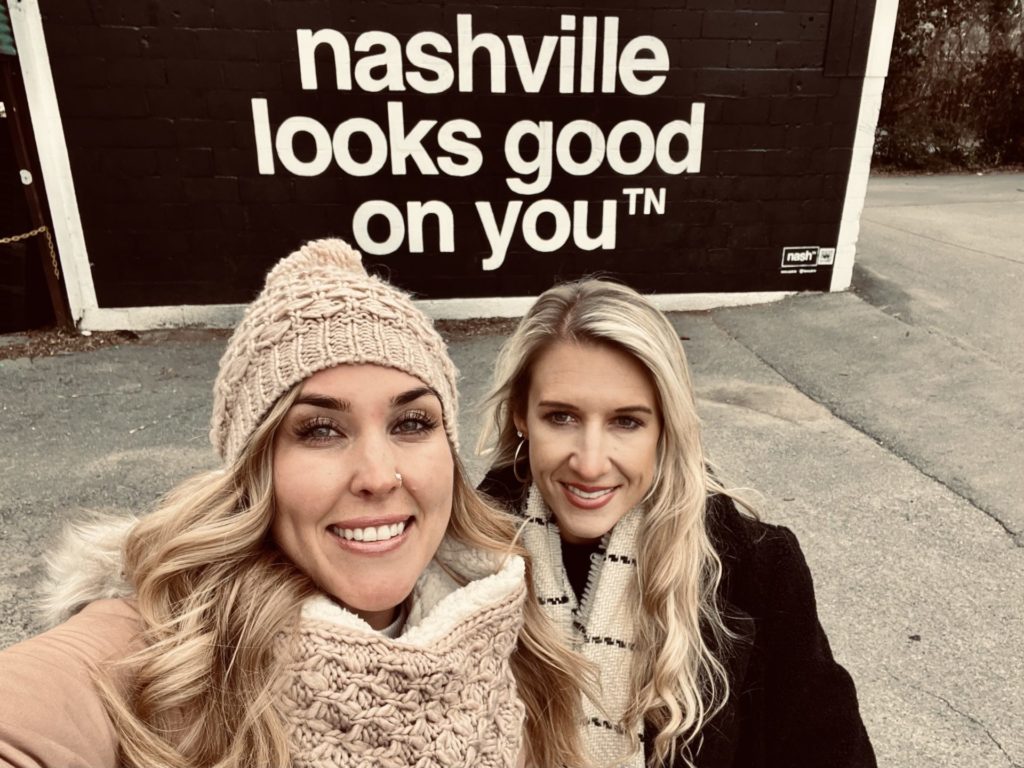 Erinn and Olivia pose in front of a mural that says "Nashville looks good on you."
