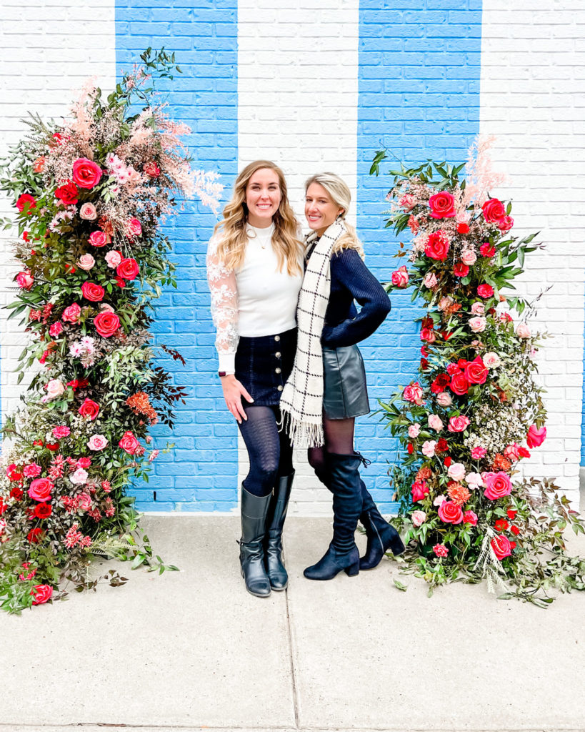 Erinn and Olivia stand in front of a blue and white striped wall in Nashville.