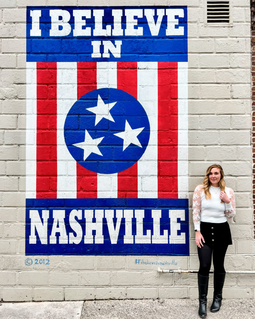 Erinn stands in front of a mural that says "I BELIEVE IN NASHVILLE."